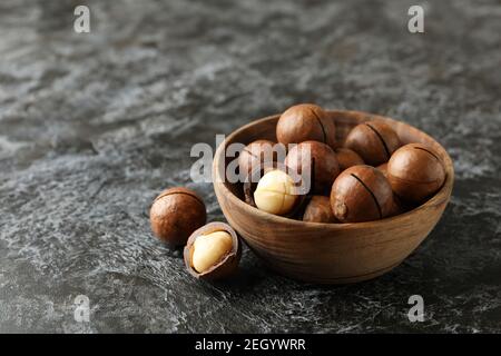 Schüssel mit leckeren Macadamia-Nüssen auf schwarzem rauchigen Hintergrund Stockfoto