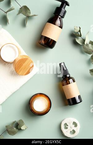 Set von Bernstein Glas kosmetischen Flaschen, Gläser Feuchtigkeitscreme, Loofah, Eukalyptus Blätter auf grünem Hintergrund. SPA natürliche Bio-Beauty-Produkte Pac Stockfoto