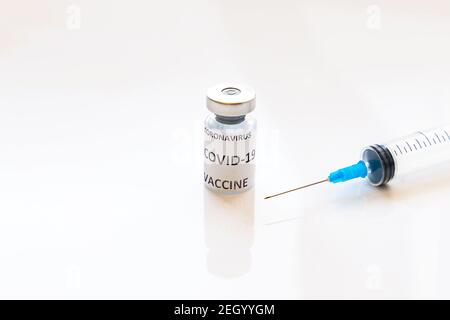 Coronavirus COVID-19-Impfstoff Fläschchen und Spritze auf glänzend weißem Hintergrund Stockfoto