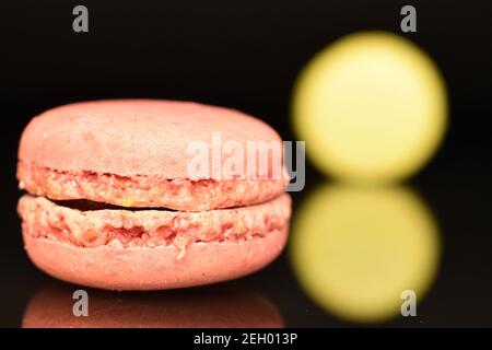 Ein ganzer aromatischer süßer köstlicher Macaron auf schwarzem Hintergrund. Stockfoto