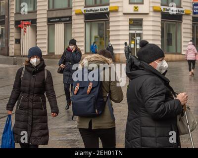 Brünn, Tschechische Republik. 02-17-2021. Menschen mit Gesichtsmaske vor Corona Virus zu schützen Spaziergang auf Masarykova Straße mit Bank Raiffeinsen Bank auf backgroun Stockfoto