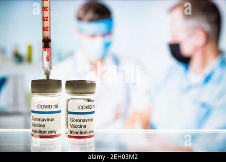 Close-up-Impfstoff COVID-19. Ärztin mit OP-Maske und in Handschuhen, die dem Mann im Krankenhaus Impfstoffinjektion verabreichen. Impfung während des Coronavirus Stockfoto
