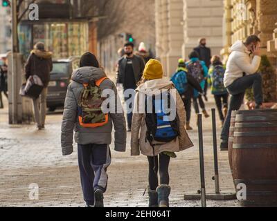 Brünn, Tschechische Republik. 02-17-2021. Zwei Jugendliche Kinder aus der Schule zu Fuß auf Cheska Straßenbahnhaltestelle in der Stadt Brünn am kalten Wintertag. Stockfoto