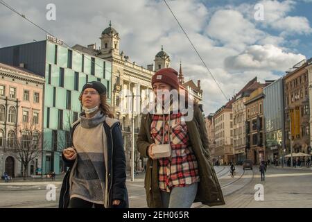 Brünn, Tschechische Republik. 02-17-2021. Zwei junge trendige Frauen zu Fuß und im Gespräch auf dem Platz der Freiheit in der Stadt Brünn im Winter. Stockfoto