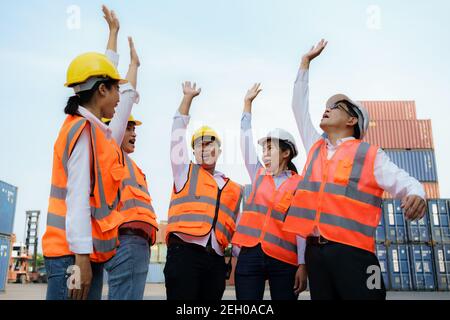 Asiatischer Vorarbeiter und sein Team-Personal in der Container-Depot Terminal Arm heben Feier erfreut, ihre Ziele Erfolg Arbeit zu erreichen. Stockfoto