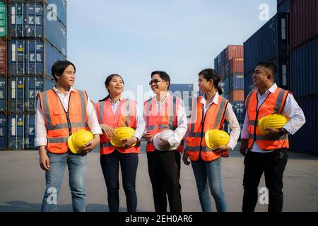 Asiatischer Vorarbeiter und Mitarbeiter ruhen sich aus und unterhalten sich nach der Arbeit am Abend im Container-Depot-Terminal. Stockfoto