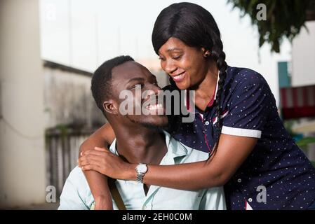 Junges afrikanisches Paar umarmt sich und schaut sich lachend an. Stockfoto