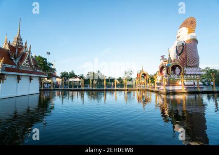 KOH SAMUI, THAILAND - 10. Januar 2020: Frau in einem roten Kleid steht auf einer Brücke zu einer riesigen bunten buddha-Statue am Wat Plai laem Tempel auf koh Stockfoto