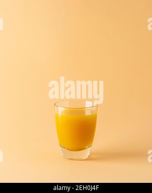 Köstlicher süßer Orangen- oder Mangosaft im Glas isoliert auf Beigefarbener Hintergrund Stockfoto