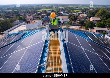 Ein asiatischer Techniker überprüft die Wartung der Solarmodule auf dem Dach. Stockfoto