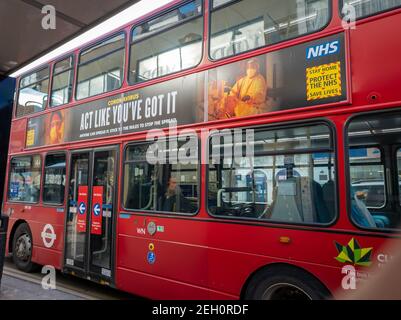 Ein Londoner Doppeldeckerbus mit einer Sicherheitswerbeanzeige des NHS Covid-19 auf seiner Seite. Stockfoto