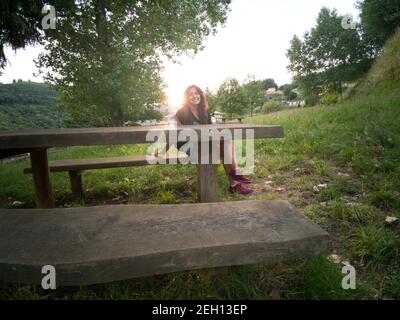 Schöne Brünette Frau vor dem See auf Picknick gestützt Tabelle Stockfoto