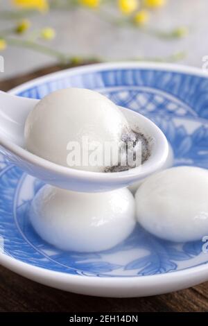 Nahaufnahme von Yuanxiao tangyuan (klejeous Reis Knödel Bälle) in einer Schüssel auf grauen Tisch mit Blume, Nahrung für chinesische Laterne Yuanxiao Festival. Stockfoto