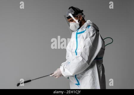 In voller Länge Profilaufnahme eines Sanitäters in einem gefahrstoffanzug mit isoliertem Spray auf weißem Hintergrund Stockfoto