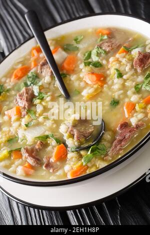 Scotch Brühe ist eine traditionelle schottische Suppe aus Lamm, und Gemüse, Gerste, Erbsen in der Nähe auf dem Teller auf dem Tisch. Vertikal Stockfoto