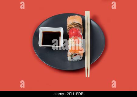 Gemischte Sushi-Rollen auf einem schwarzen Teller mit Saucen Stockfoto