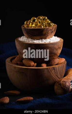 Stillleben, gesundes Lebensmittelkonzept, drei Schalen mit Mandelnüssen, Pulver und Gelatinekapseln in Form einer Pyramide Stockfoto