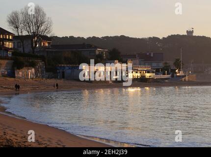 Heterosexuelle Paare, die an einem sonnigen Morgen am Strand Playa de los Bikinis am Rande der Bucht von Santander Cantabria Spanien spazieren gehen Stockfoto