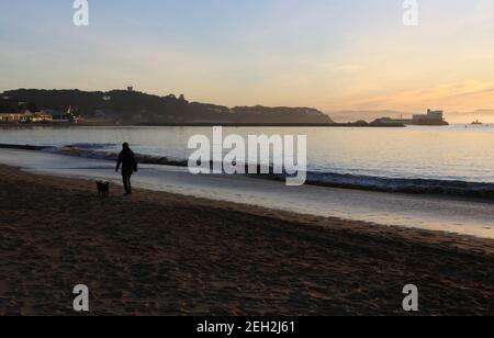 Frau, die mit einem Hund am Strand Playa de los Bikinis läuft Santander Cantabria Spanien Winter ruhiger, sonniger Morgen Stockfoto