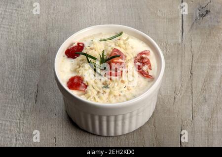 Ein Topf mit Auflauf - saure Sahne, Tomaten und Fisch oder andere Zutaten vor dem Backen. Gerichte mit ungebratenen Julienne Stockfoto