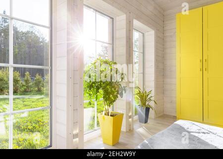 Helles Interieur, Zimmer in Holzhaus mit großem Fenster. Skandinavischer Stil. Die trendigen Farben von 2021 sind grau und gelb Stockfoto