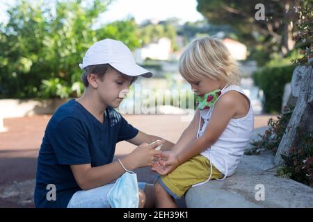 Kinder, Jungen Brüder, Masken tragen und Desinfektion im Freien Stockfoto