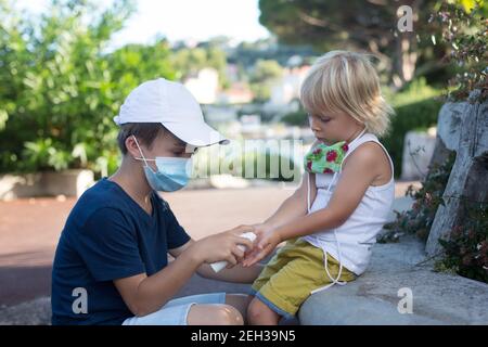 Kinder, Jungen Brüder, Masken tragen und Desinfektion im Freien Stockfoto