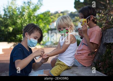 Kinder, Jungen Brüder, Masken tragen und Desinfektion im Freien Stockfoto