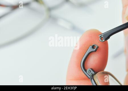 Gebrochene Brille und Schraubendreher auf grauem Hintergrund. Brillen Reparaturkonzept. Nahaufnahme. Stockfoto