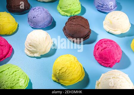 Bunte verschiedene Eisbecher Muster auf pastellblauem Hintergrund. Sommer Minimalismus Muster flach Lay mit hartem Licht. Schokolade Vanille Blaubeere s Stockfoto