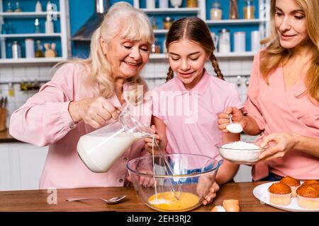 Schöne ältere Frau und Familie Backen in der Küche - Großmutter Vorbereitung Desserts zu Hause mit Tochter und Neffen, Konzepte über das Kochen und Stockfoto