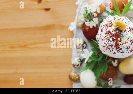 Köstliches hausgemachtes Osterbrot, stilvolle ostereier, blühende Frühlingsblumen auf rustikalem Tisch, Draufsicht. Frohe Ostern! Leerzeichen für Text. Modern natürlich Stockfoto