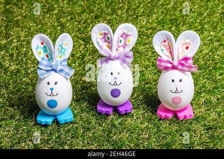 Traditionelles festliches Osterkonzept. Bunte niedliche handgemachte Kaninchen aus Eiern auf grünem Gras Hintergrund, kopieren Raum Stockfoto