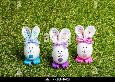 Traditionelles festliches Osterkonzept. Bunte niedliche handgemachte Kaninchen aus Eiern auf grünem Gras Hintergrund, kopieren Raum Stockfoto
