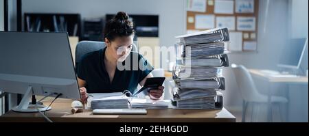 Junge Geschäftsfrau, Die Im Büro Mit Stapel Von Ordnern Auf Dem Schreibtisch Arbeitet Stockfoto