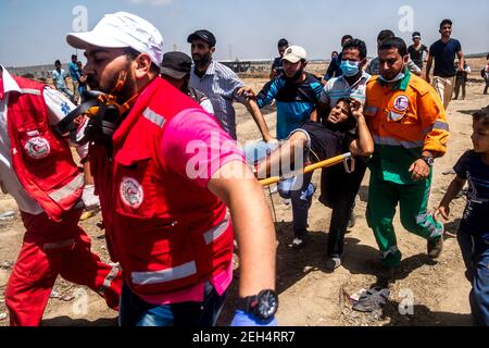 Ein Mann mit Schussverletzungen wird zu einem Krankenwagen gebracht, von wo aus er zur Behandlung aus dem Bereich evakuiert wird. Die Spannungen entlang der Grenze zwischen Gaza und Israel sind hoch, nachdem mehr als einen Monat lang wöchentlich Massenproteste in der Nähe der Barriere stattfanden, bei denen 50 palästinensische Demonstranten getötet und mehr als 1.700 durch israelische Schüsse verletzt wurden. Die Hamas-Führer in Gaza haben versprochen, dass die Märsche fortgesetzt werden, bis die zehnjährige israelische Blockade des Territoriums aufgehoben wird. Proteste werden auch am 14. Und 15. Mai erwartet, dem Tag, an dem Palästinenser Yawm an-Nakba oder "Tag der Katastrophe" zum Gedenken an den Jahrestag begehen werden Stockfoto