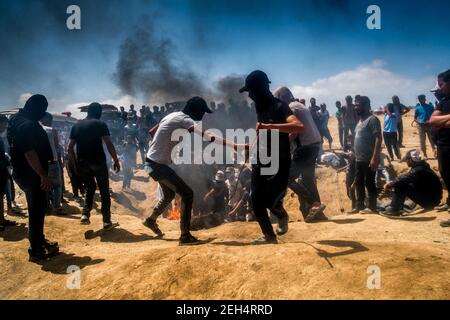 Ein Demonstrator schießt einen brennenden Reifen, um eine Rauchsperre zu schaffen und anderen zu erlauben, Steine zu werfen, ohne durch das Scharfschützenfeuer der israelischen Armee alarmiert zu werden. Die Spannungen entlang der Grenze zwischen Gaza und Israel sind nach mehr als einem Monat wöchentlicher Massenproteste in der Nähe der Barriere, bei denen 50 palästinensische Demonstranten getötet und mehr als 1.700 durch israelische Militärfeuer verletzt wurden, hoch. Die Hamas-Führer in Gaza haben versprochen, dass die Märsche fortgesetzt werden, bis die zehnjährige israelische Blockade des Territoriums aufgehoben wird. Proteste werden auch am 14. Und 15. Mai erwartet, dem Tag, an dem die Palästinenser Yawm an-Nakba oder den Tag der DISAs feiern werden Stockfoto