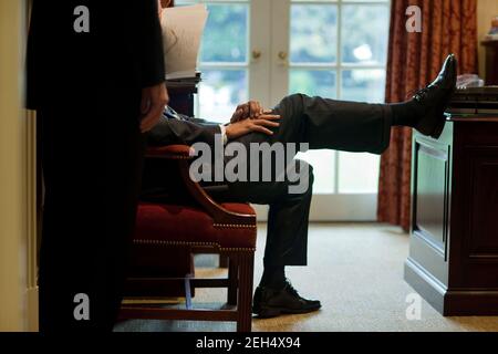 Präsident Barack Obama ruht seinen Fuß auf einem Schreibtisch, während er mit Phil Schiliro, dem Assistenten des Präsidenten für legislative Angelegenheiten, im Outer Oval Office am 29. Oktober 2009 spricht. Stockfoto