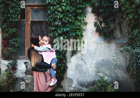 Glückliche liebevolle Familie. Mama hält ihr Töchterkind in den Armen und küsst sie auf die Stirn. Mutter und Tochter. Stockfoto