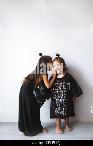 Zwei kleine Mädchen plaudern, isoliert über weiß, Mädchen in Mama's Kleidung A gekleidet Stockfoto