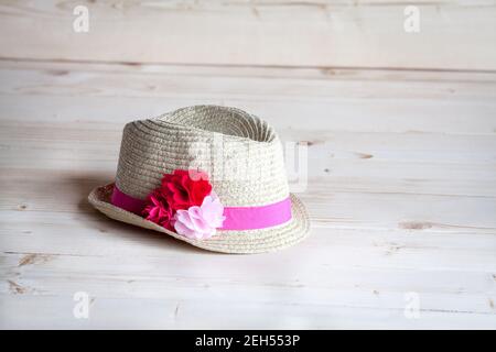 Strohhut mit Blumen auf einem hellen Holzhintergrund und Stockfoto