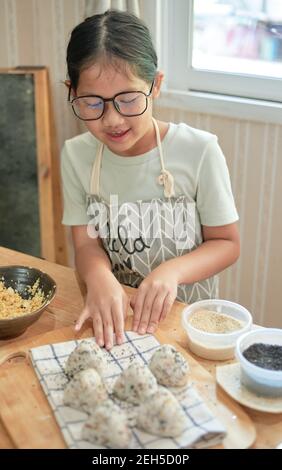 Ein Mädchen, das ein hausgemachtes Onigiri macht Stockfoto