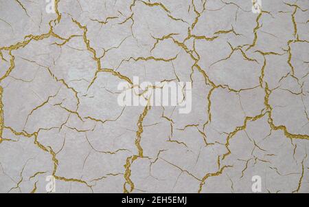 Alte antike Wand mit Rissen übermalt mit Goldfarbe Stockfoto