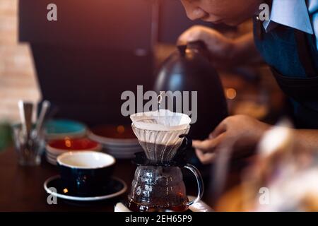 Barista gießt kochendes Wasser aus dem Wasserkocher in die Kaffeemaschine. Stockfoto