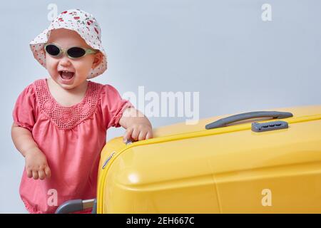 Portrait eines lachenden Mädchens mit einem großen Koffer in den Händen. Reise- und Freizeitkonzept mit Copyspace Stockfoto