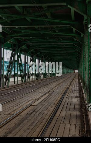 Lange Holz- und Metallbrücke mit Straßenbahnschienen und grün Konstruktion Stockfoto