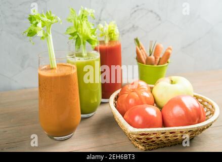 Drei Gläser mit Karotten-, Sellerie- und Tomatensaft auf Holzgrund. Stockfoto