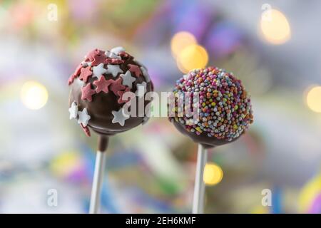 Nahaufnahme von zwei Cake Pops mit Schokolade und Dekoration mit Zucker in Sternform, Bokeh im Hintergrund Stockfoto