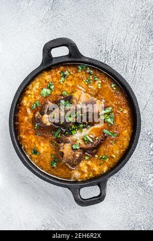 Kharcho-Suppe mit Rindfleisch, Reis, Tomaten und Gewürzen in einer Pfanne. Weißer Hintergrund. Draufsicht Stockfoto