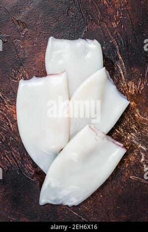 Rohe Tintenfisch- oder Calamari-Röhren auf einem Küchentisch. Dunkler Hintergrund. Draufsicht Stockfoto